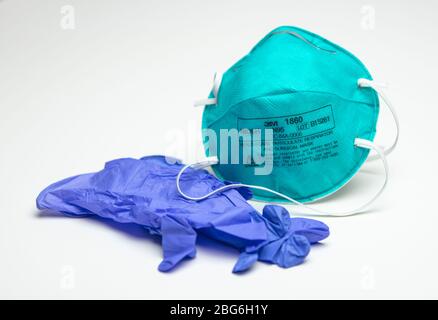 Houston, TX - 20. April 2020: Eine unbenutzte, türkisfarbene 3M N95 Atemschutzmaske neben einem blauen Paar Gummihandschuhe. Stockfoto