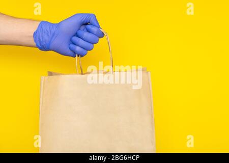 Lieferung Mann in medizinischen Handschuhen hält Papier Handtasche mit Lebensmittelbehältern, Lieferungen aus dem Lebensmittelgeschäft isoliert. Safe kontaktlosen Lieferservice, Stockfoto