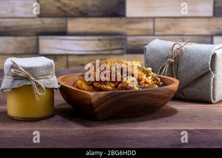 Glas mit Honig und eine Holzplatte mit Honig in Waben auf einem hölzernen Hintergrund Stockfoto