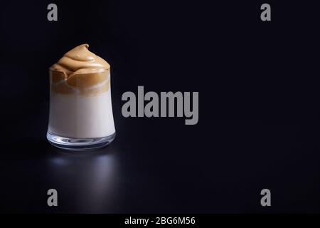 Iced koreanischen Dalgona-Kaffee, ein trendiger flauschiger cremig Schlagsahne Kaffee auf schwarzem Hintergrund. Kopierbereich Stockfoto