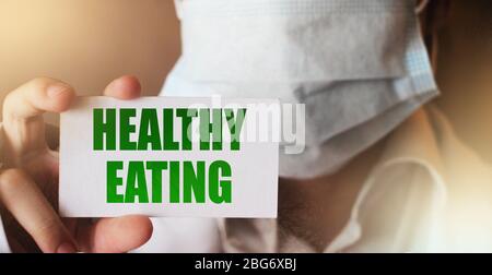 Arzt hält eine Karte mit den Worten gesunde Ernährung geschrieben. Adipositas Problem, gesunde Ernährung Diät Schlankheitskonzept Stockfoto