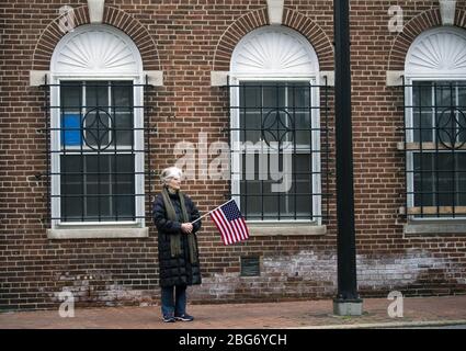 Annapolis, Usa. April 2020. Eine Frau hält eine amerikanische Flagge, während sie am Montag, den 20. April 2020, während der Coronavirus COVID-19-Pandemie in Annapolis, Maryland, auf der Main Street wartet. Foto von Kevin Dietsch/UPI Stockfoto