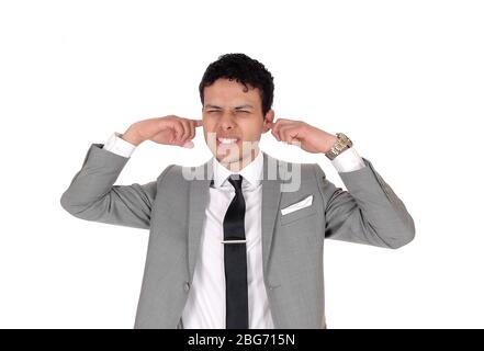 Ein schöner junger Mann in einem grauen Anzug, der mit den Fingern im Ohr steht, hört nicht gerne, isoliert auf weißem Hintergrund Stockfoto