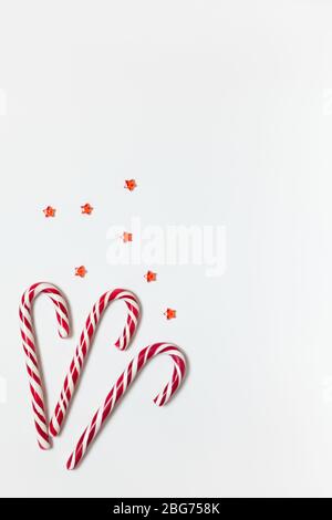 Weihnachten Zusammensetzung drei Karamell Zuckerstangen, Konfetti Sterne auf weißem Hintergrund mit kopieren. Festliche minimal style Flach. Für Grußkarte Stockfoto