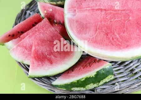 Reife Wassermelonen auf Korbtablett auf Holztisch Stockfoto