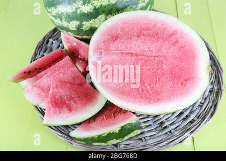 Reife Wassermelonen auf Korbtablett auf Holztisch Stockfoto