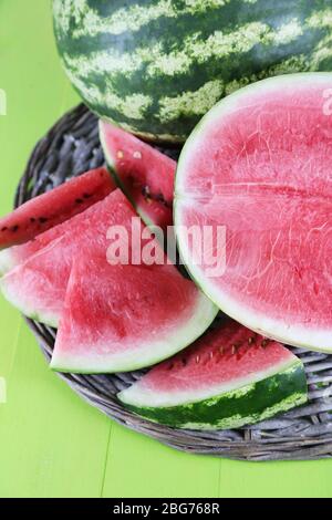 Reife Wassermelonen auf Korbtablett auf Holztisch Stockfoto