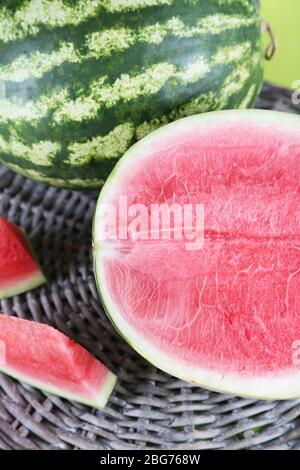 Reife Wassermelonen auf Korbtablett auf Holztisch Stockfoto