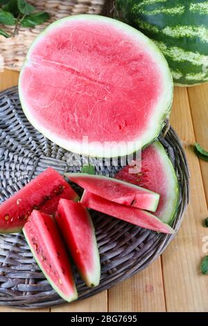 Reife Wassermelonen auf Korbtablett auf Holztisch Stockfoto