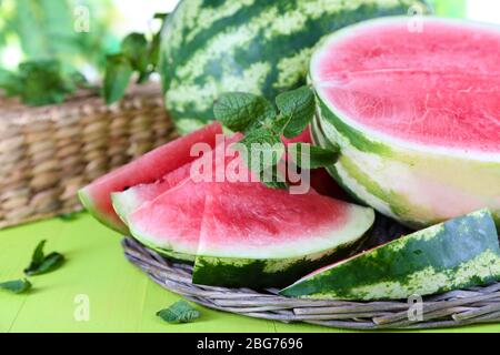 Reife Wassermelonen auf Weidenschale auf Holztisch auf Naturhintergrund Stockfoto