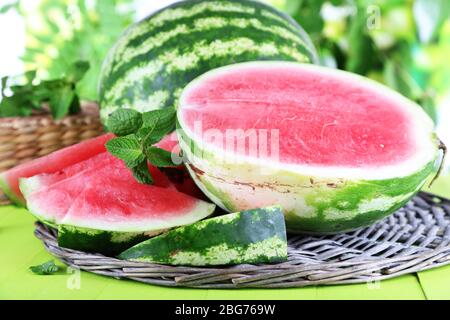 Reife Wassermelonen auf Weidenschale auf Holztisch auf Naturhintergrund Stockfoto