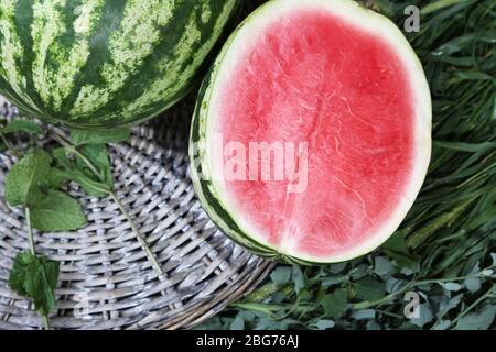 Reife Wassermelonen auf Weidenschale auf Gras Stockfoto