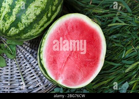 Reife Wassermelonen auf Weidenschale auf Gras Stockfoto