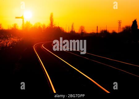 Sonnenuntergang auf der Warrington Low Level Güterbahnlinie, die auf den Schienen mit einem Semaphore Fernsignal glänzen Stockfoto