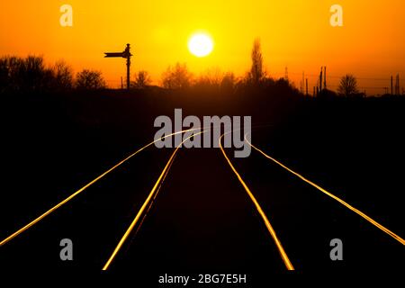 Sonnenuntergang auf der Warrington Low Level Güterbahnlinie, die auf den Schienen mit einem Semaphore Fernsignal glänzen Stockfoto