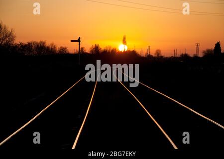 Sonnenuntergang auf der Warrington Low Level Güterbahnlinie, die auf den Schienen mit einem Semaphore Fernsignal glänzen Stockfoto