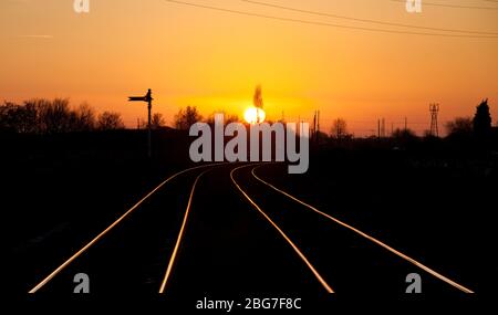 Sonnenuntergang auf der Warrington Low Level Güterbahnlinie, die auf den Schienen mit einem Semaphore Fernsignal glänzen Stockfoto