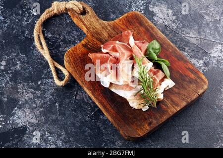 Italienischer Prosciutto crudo oder Jamon mit Rosmarin. Vorspeise aus rohem Schinken Stockfoto
