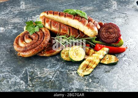 Verschiedene köstliche gegrilltes Fleisch mit Gemüse auf einem Grill mit gegrillten Würstchen und Gemüse. Hintergrund und Würstchen Stockfoto