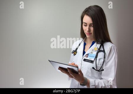 Frau mit Technologie für das Gesundheitswesen. Mit Tech zur Verbesserung der Gesundheit. Weiblich auf grauem Hintergrund Stockfoto