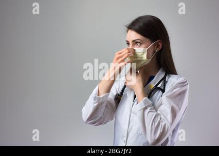 Frau Gesundheitsfachkraft demonstriert ordnungsgemäße Anziehen der Maske zum Schutz vor Coronavirus. Bis nahe weibliche Gesundheitsarbeiter setzen auf Safet Stockfoto