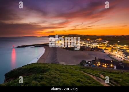 West Bay, Dorset, Großbritannien. April 2020. Wetter in Großbritannien. Die Wolken leuchten nach Sonnenuntergang im Seebad West Bay in Dorset kurz rot, während das Wetter diese Woche mit steigenden Temperaturen weitergeht. Bild: Graham Hunt/Alamy Live News Stockfoto