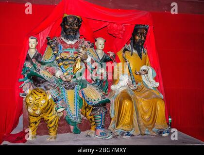 Fengdu, China - 8. Mai 2010: Geisterstadt, historisches Heiligtum. Bunte Gruppenstatue von Yin und Wang, Gründer der religiösen Stätte, mit einem Tiger. Rot Stockfoto