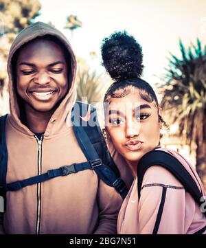 Ein lächelnder Mann und eine schöne junge Frau von Farbe, genießen Sie das Campusleben mit ihrer frechen Haltung und zuckerten Lippen mit trendy up-do Frisur, Tucson, AZ Stockfoto