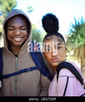 Ein lächelnder Mann und eine schöne junge Frau von Farbe, genießen Sie das Campusleben mit ihrer frechen Haltung und zuckerten Lippen mit trendy up-do Frisur, Tucson, AZ Stockfoto