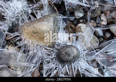 Bunte Felsen umgeben von sternenartigen Eisformationen in einem kleinen Bach Stockfoto