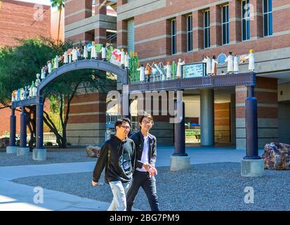 Zwei junge Männer asiatischer Abstammung lachen vor dem Henry Koffler Gebäude mit den Skulpturen der Wissenschaftler an der Universität von Arizona, Tucson, AZ Stockfoto