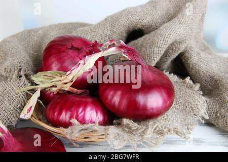 Frische rote Zwiebeln in Korbkorb auf dem Tisch Nahaufnahme Stockfoto