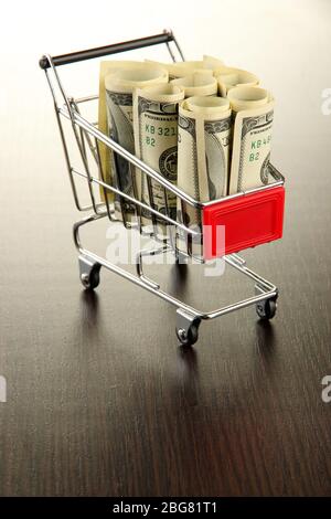 Einkaufswagen mit Dollar, auf dunklem Hintergrund Stockfoto