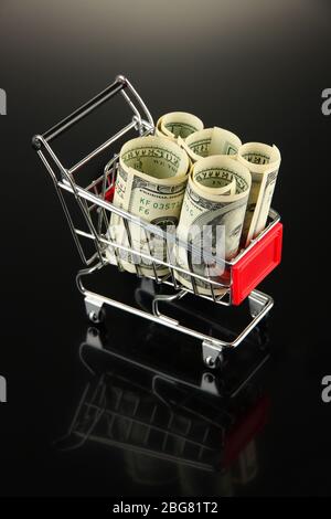 Einkaufswagen mit Dollar, auf dunklem Hintergrund Stockfoto