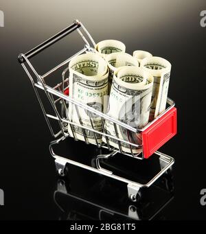 Einkaufswagen mit Dollar, auf dunklem Hintergrund Stockfoto