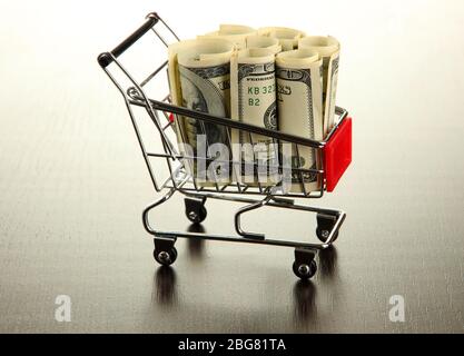 Einkaufswagen mit Dollar, auf dunklem Hintergrund Stockfoto