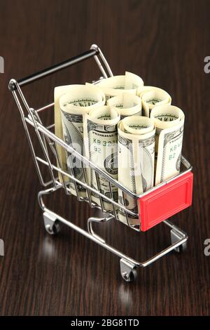 Einkaufswagen mit Dollar, auf dunklem Hintergrund Stockfoto