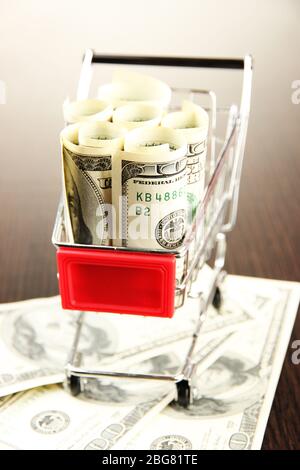 Einkaufswagen mit Dollar, auf dunklem Hintergrund Stockfoto