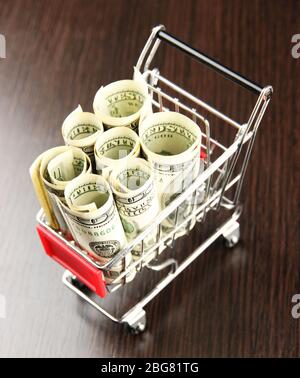 Einkaufswagen mit Dollar, auf dunklem Hintergrund Stockfoto