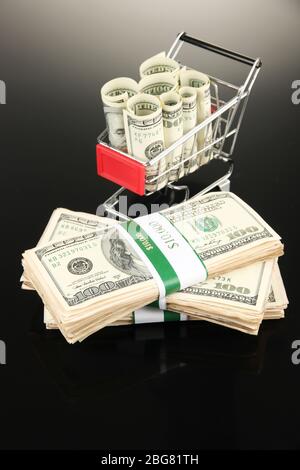 Einkaufswagen mit Dollar, auf dunklem Hintergrund Stockfoto