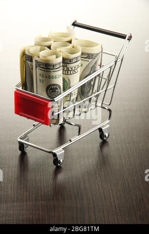 Einkaufswagen mit Dollar, auf dunklem Hintergrund Stockfoto