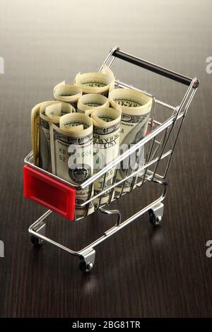 Einkaufswagen mit Dollar, auf dunklem Hintergrund Stockfoto