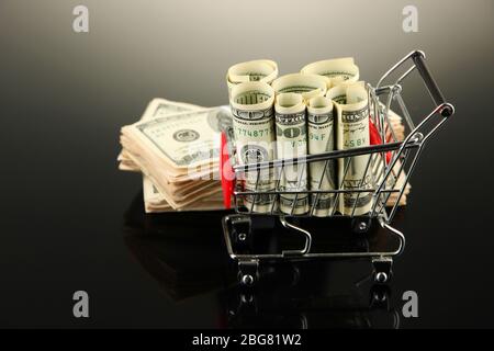 Einkaufswagen mit Dollar, auf dunklem Hintergrund Stockfoto