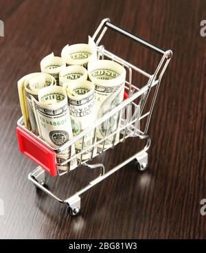 Einkaufswagen mit Dollar, auf dunklem Hintergrund Stockfoto