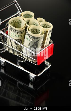 Einkaufswagen mit Dollar, auf dunklem Hintergrund Stockfoto
