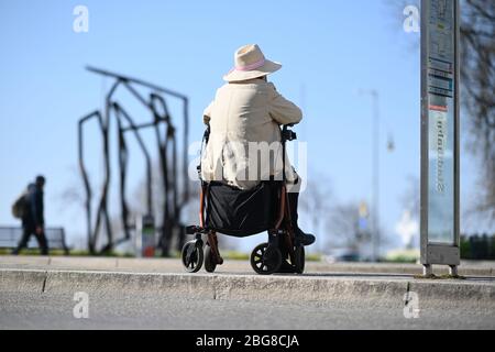 Friedrichshafen, Deutschland. April 2020. Eine ältere Bürgerin sitzt auf ihrem Geher am Busbahnhof am Bodensee und wartet auf einen Bus. (Zu dpa: ''Wir haben wenige Kontakte' - als Busfahrer während der Corona-Zeiten unterwegs') Quelle: Felix Kästle/dpa/Alamy Live News Stockfoto