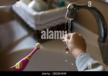 Waschen Sie die Zahnbürste unter das Wasser im Waschbecken, morgen Hygiene Stockfoto