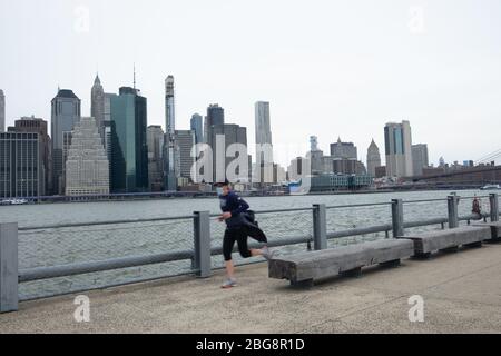 New York City, USA. April 2020. Ein Mann, der joggt, trägt eine Gesichtsmaske als vorbeugende Maßnahme gegen die Ausbreitung des Coronavirus im Brooklyn Bridge Park.die Vereinigten Staaten haben 40,000 bestätigte Todesfälle durch Coronavirus übertroffen, wobei New York das Epizentrum der Krankheit ist. Quelle: Braulio Jatar/SOPA Images/ZUMA Wire/Alamy Live News Stockfoto