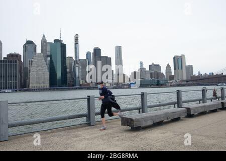 New York City, Usa. April 2020. Ein Mann, der joggt, trägt eine Gesichtsmaske als vorbeugende Maßnahme gegen die Ausbreitung des Coronavirus im Brooklyn Bridge Park.die Vereinigten Staaten haben 40,000 bestätigte Todesfälle durch Coronavirus übertroffen, wobei New York das Epizentrum der Krankheit ist. Quelle: SOPA Images Limited/Alamy Live News Stockfoto