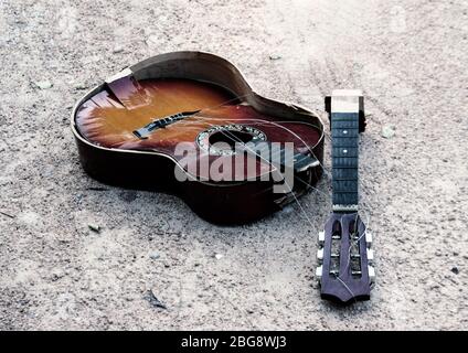 Kaputte Gitarre auf Sand im traurigen Song Emotion Konzept am Sandstrand. Stockfoto